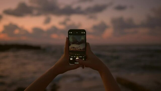 Young european women girl by the sea, takes a selfie and photographs the sunset.