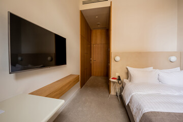 tv flat screen on wall near comfortable bed with pillows in hotel room.