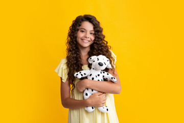 Teen girl child in casual wear holding plush toy isolated on yellow background, happy childhood....