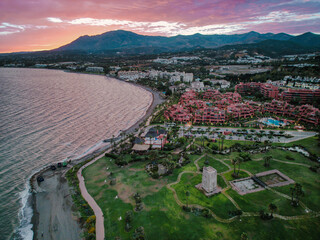 Aerial View of Appartments and the watchtower of guadalmansa by the beach in Estepona, Spain. In the back is the sierra bermeja mountain