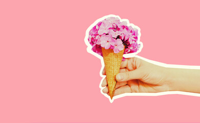 Hand holding cone ice cream with flowers on pink background, magazine style