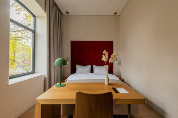 wooden desk and chair near comfortable bed in hotel room.