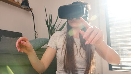 Young woman using virtual reality equipment, VR glasses, to look around the artificial world