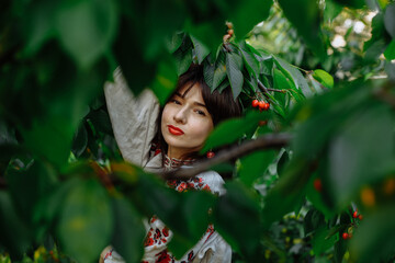 Beautiful girl in national clothes outdoors on the background of a green field and trees