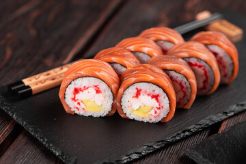 Sushi roll philadelphia with salmon and avocado and cream cheese, caviar on black background close-up. Sushi menu. Japanese food concept