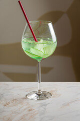 cucumber lemonade with wine glass on marble table vertical
