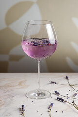 cocktail with lavender on a white marble table vertical