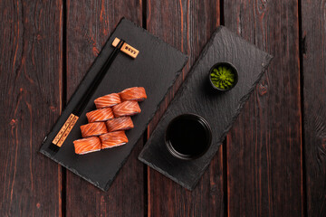 Sushi roll philadelphia with salmon and avocado and cream cheese, caviar on black background top view. Sushi menu. Japanese food concept