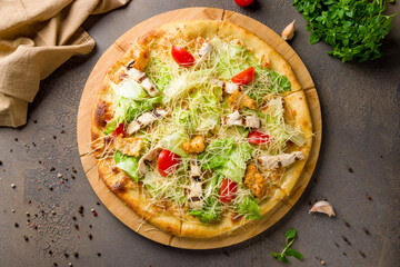 Pizza Caesar with chicken and green salad on wooden board top view