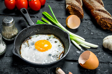 Fried egg in a pan with bread and tomatoes.