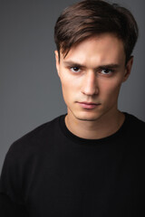 Fototapeta premium A guy of model appearance in black clothes poses on a gray studio background. Male fashion portrait