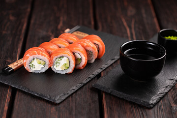 Sushi roll philadelphia with salmon and cucumber with avocado and cream cheese on black background. Sushi menu. Japanese food concept