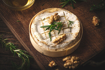 French cheese Camembert baked in a wooden box served with honey, aromatic herbs and nuts. Taste of France, rustic style