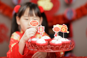 young girl was decorating cupcake for Chinese new year party against with traditional Chinese 