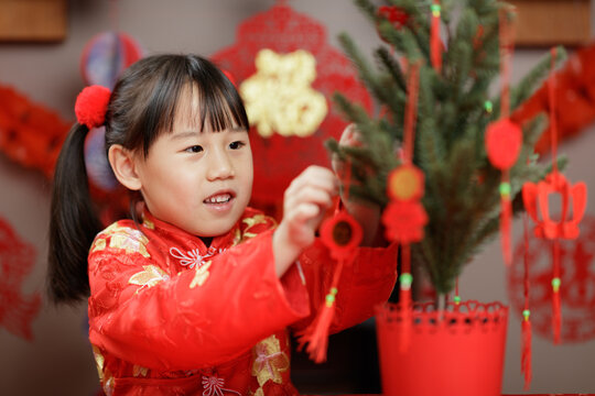 young girl was decorating Chinese New year greeting card against with traditional Chinese "FU" means" lucky" greeting decorating sign background