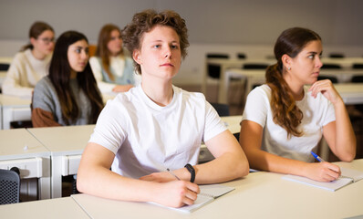 A young student is carefully recording a lecture by a school teacher