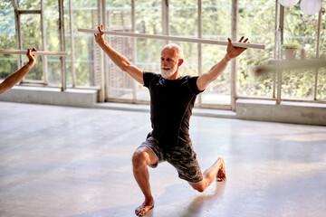 Mature man doing stick yoga