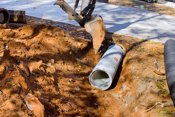 Worker working with tractor lift to install sewage pipes in ground is preparing install concrete...