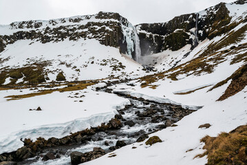 Scenic view of the picturesque Grundarfoss waterfall and the river Grundará in a snow-covered late winter landscape, Snæfellsnes peninsula, Iceland