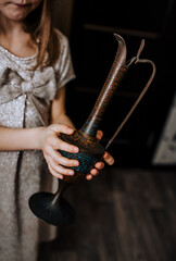 A girl, a child, who found an old lamp, rubs the jug with her hand, waiting for the genie. Photography, fantasy, magic.