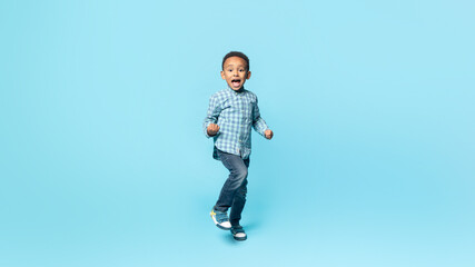 Yes. Happy little black kid boy shaking fists, making winner gesture, celebrating victory, blue...