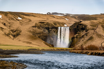 Distant view of the beautiful Skógafoss waterfall, seen from Route 1 / Ring Road over the water of...