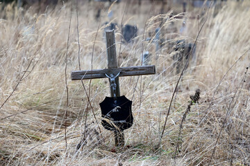 Stary  zardzewiały stalowy krzyż na cmentarzu wojennym. Krzaki.  - obrazy, fototapety, plakaty