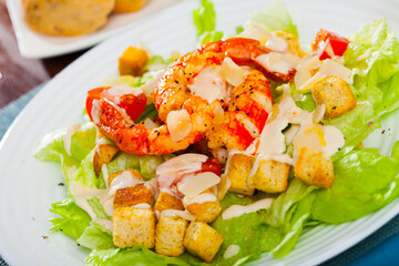 Delicious Caesar salad of romaine lettuce and croutons dressed with delicate sauce topped with shrimps and Parmesan cheese..
