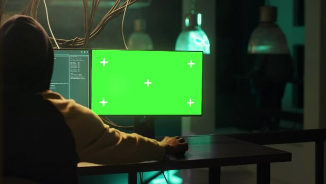 Male spy using computer display with greenscreen while stealing government information, planning cybercrime and harassment. Dangerous person breaking passwords, computer malware.