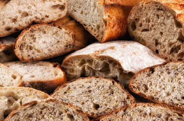 Closeup of a variety of fresh baked loaves of bread, the loaves are cut in half and sliced.
