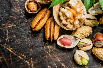Nuts background. Assortment of different nuts with green leaves .
