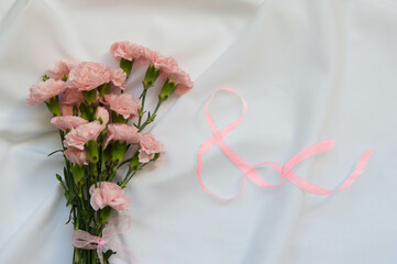 Close up photo of a pink carnation bouquet and a number 8 shapped ribbon isolated over white background