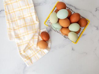 Wire Basket of Fresh Brown and Blue Chicken Eggs on White Counter