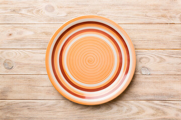 Top view of empty orange plate on wooden background. Empty space for your design