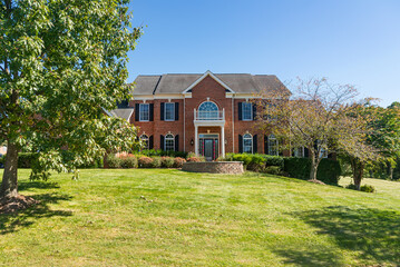 Obraz premium Large brick house with a green lawn. Sunny summer day, cloudless sky.