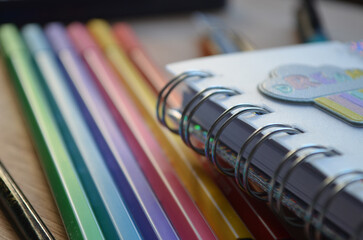 Cuaderno con espirales de cerca y marcadores de colores arcoíris