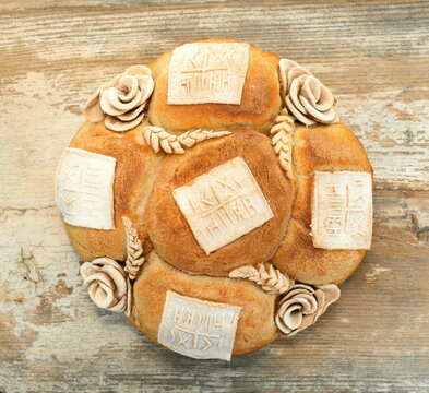 Homemade decorated Serbian slava bread on rustic wooden board.