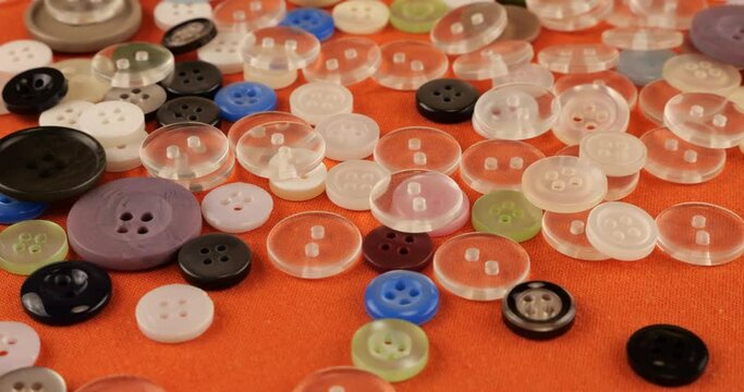 Plastic multi-colored buttons on an orange cotton fabric.
