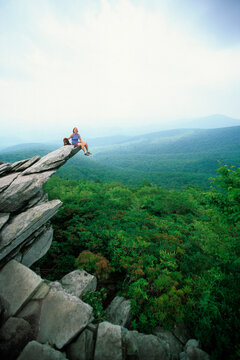Female hiker with dog checks out the view from along the Tanawha Trail above the Blue Ridge Parkway near Linville, NC