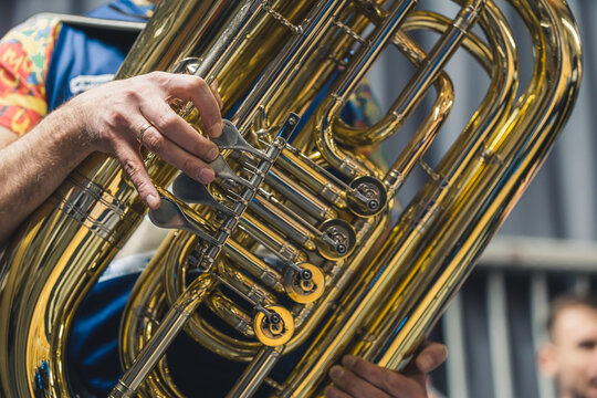 A close-up shot of a part of a tuba with a person in the background.. High quality photo