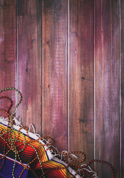 Cinco: Mexican Serape And Party Beads At Corner Of Wooden Background