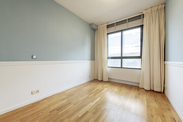 Empty living room with metal radiator under the window with heavy curtains and wooden flooring