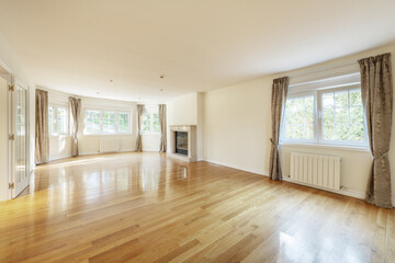 Large empty living room with marble fireplace, aluminum radiators and many French-style aluminum windows