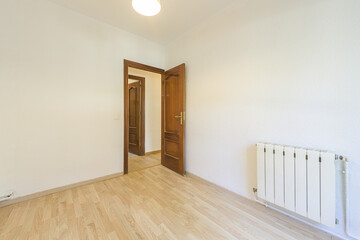 Empty room with wooden floors and sapele wood doors and aluminum sections radiator