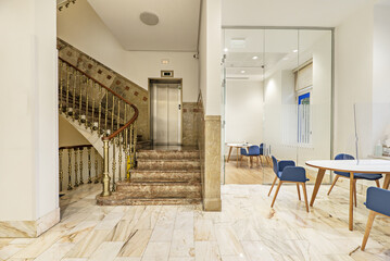 Representative marble and gold metal staircase in an office with glass partitions and wooden...
