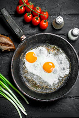 Fried eggs in a pan with bread and tomatoes.