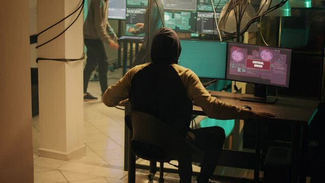 Skilled hacker successfully cracking security network on computer, doing hacking and espionage work at night. Male criminal being congratulated about cryptojacking achievement.