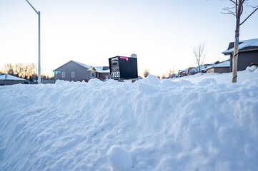 Residential mailbox blocked by a snow pile left by a plow after clearing a street.