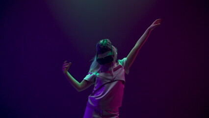 Fototapeta na wymiar Blonde woman dancing in vr glasses at neon light. 