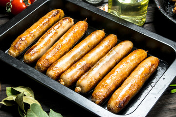 Fried sausages on a pan with herbs and spices.